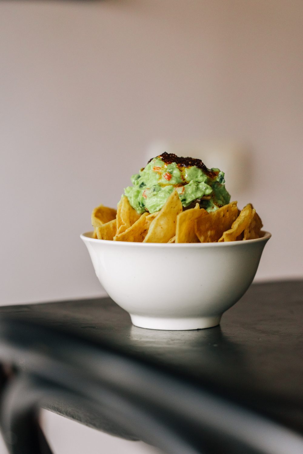 A bowl of totopos topped with guacamole and salsa macha