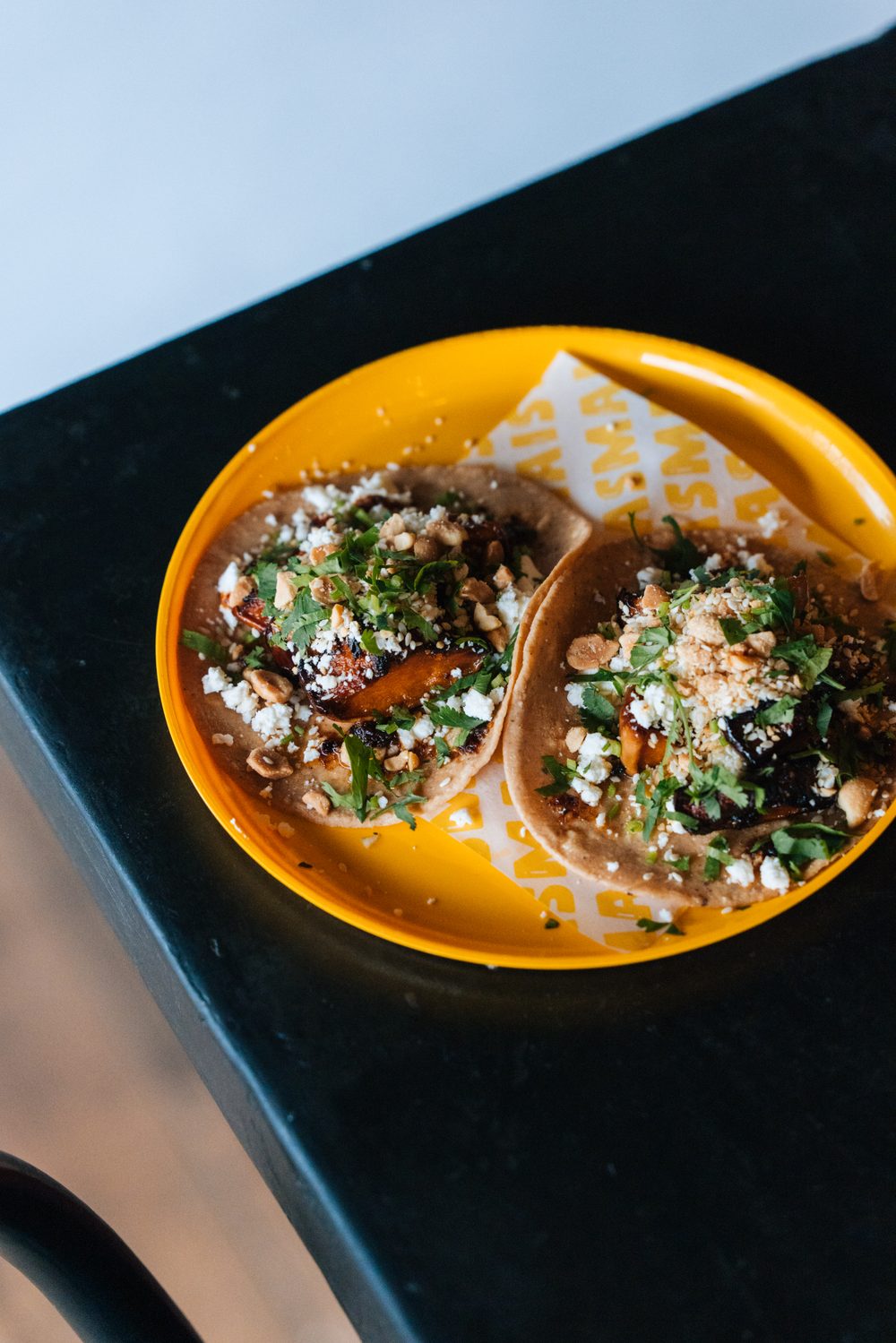 Two pumpkin tacos with feta and peanuts on a yellow MasMais plate